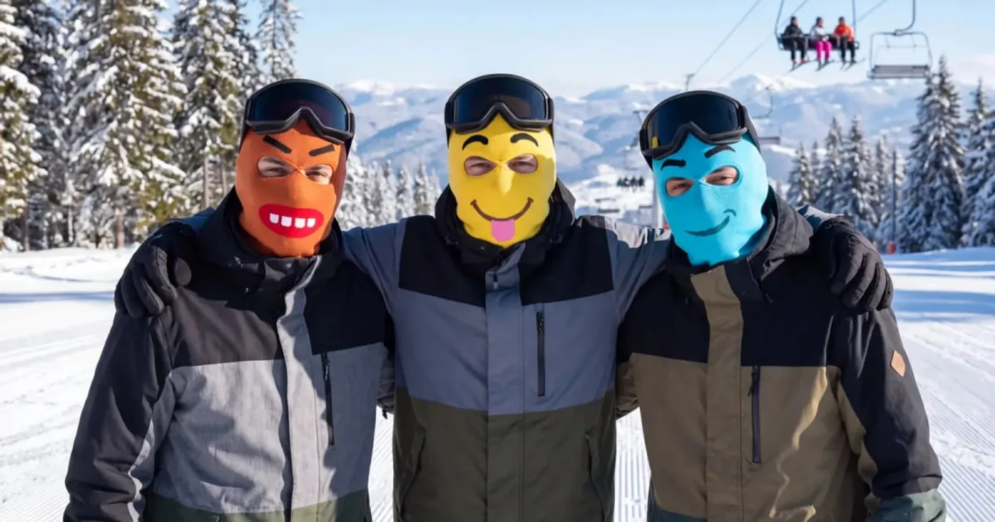 Tre skidåkare i noggos stickade skidmasker — Chomp, Derp och Grimm — på en pist med skidlift bakom.