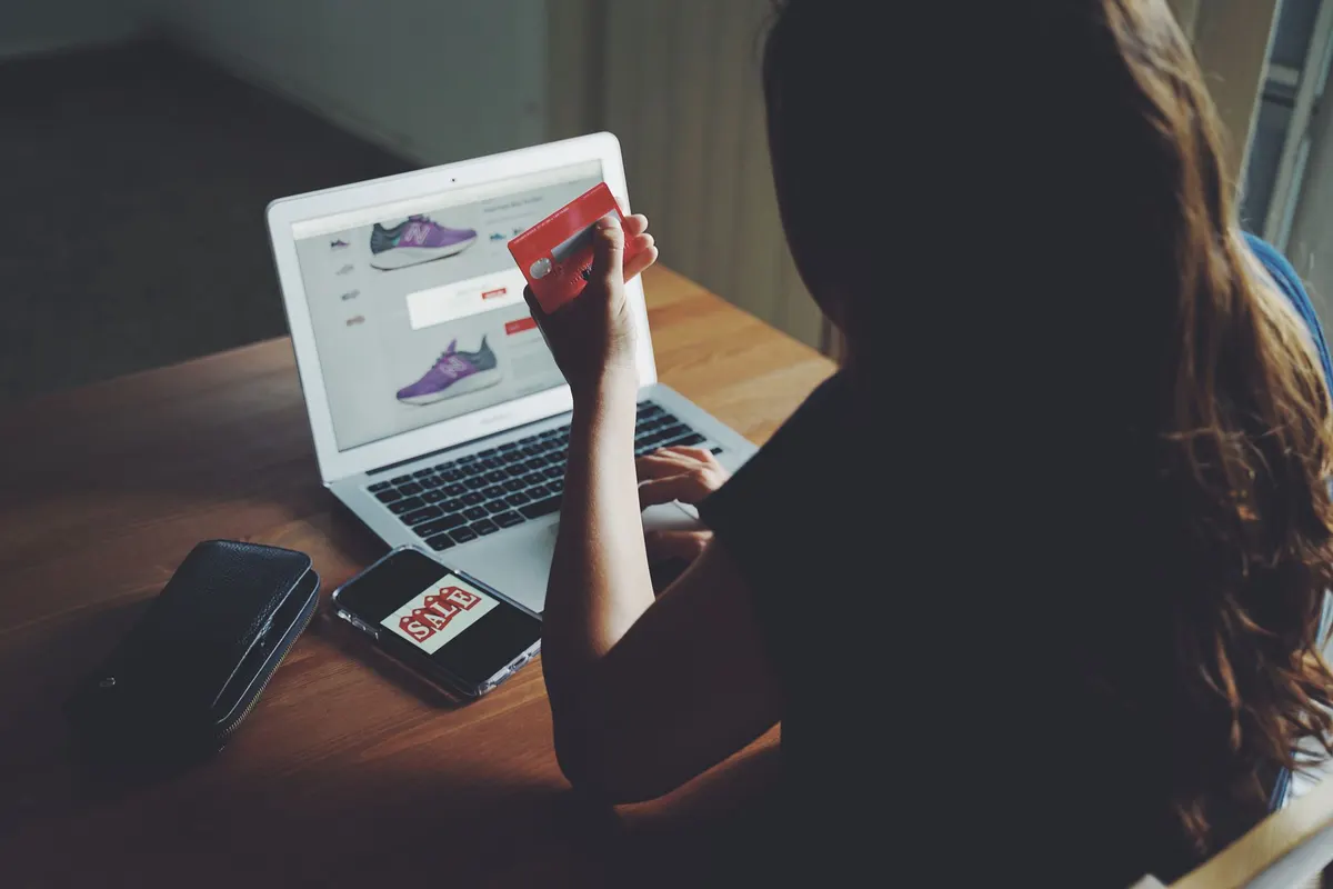 Person som handlar i en nätbutik på laptop och håller ett betalkort